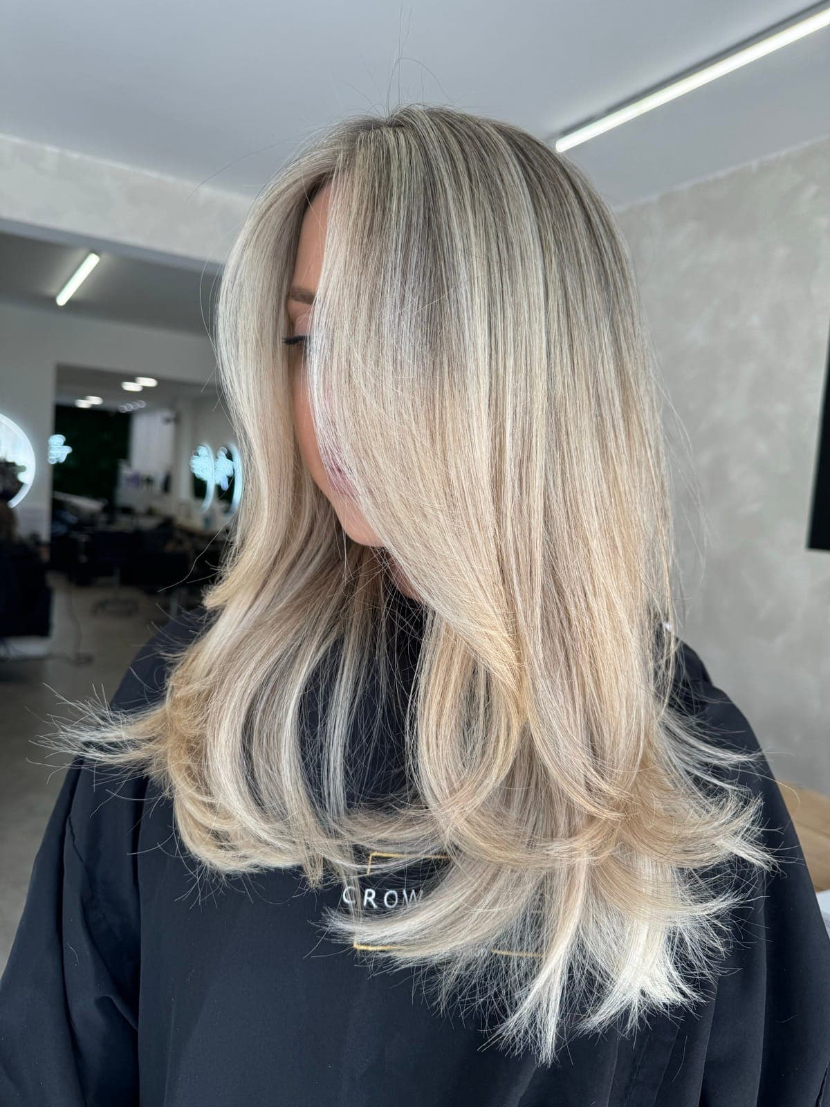 Side view of long, dimensional blonde with soft layers and gently curled ends.