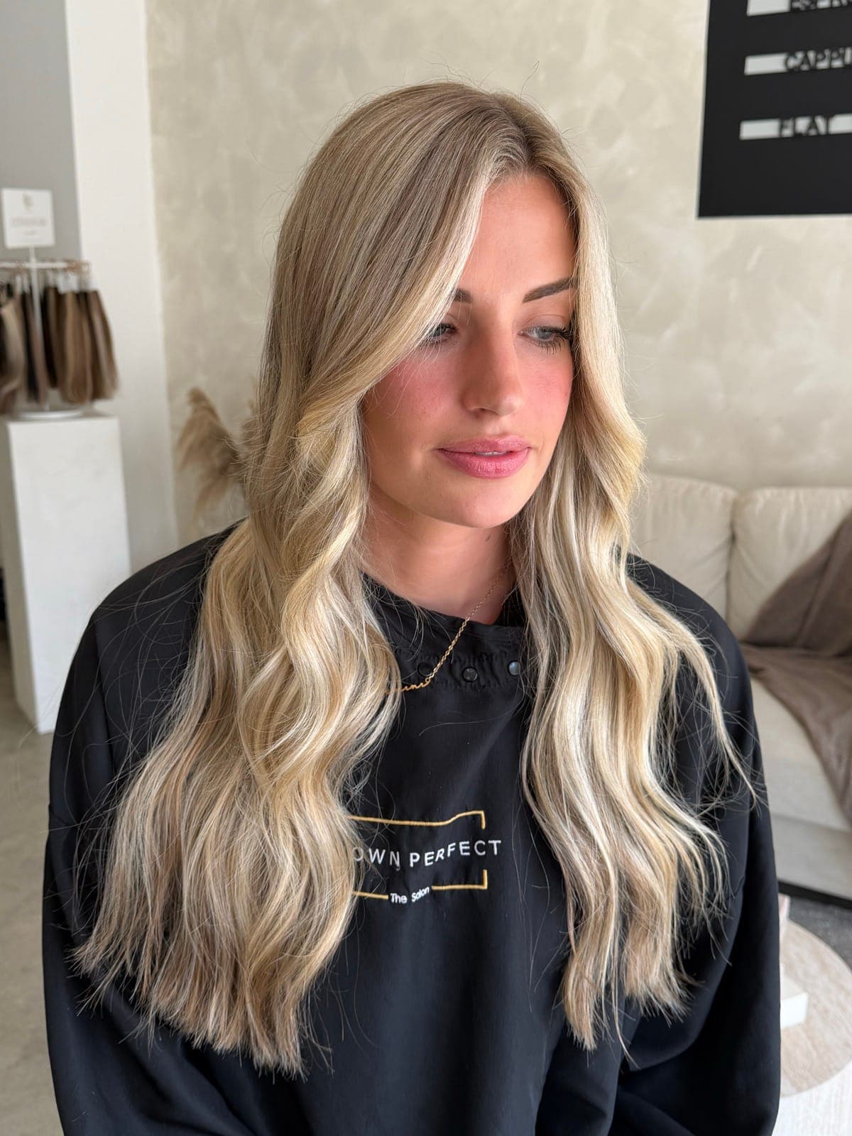 Long blonde styled in soft waves, with a lived-in balayage kept bright through the lengths.