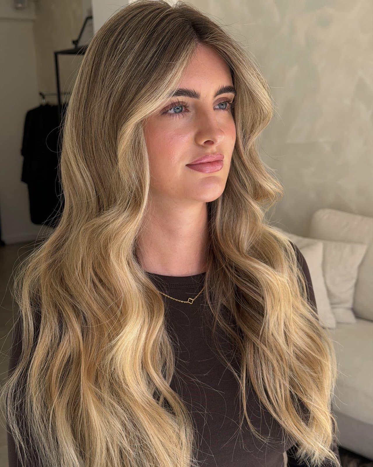 Long, wavy blonde with a sun-kissed balayage worn loose over one shoulder.