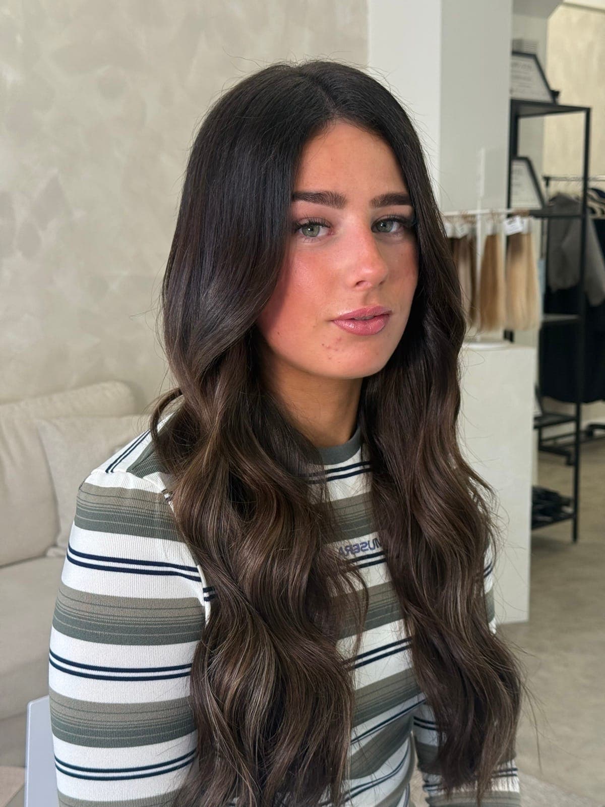 Long, deep brunette with a glossy finish and soft waves through the lengths.