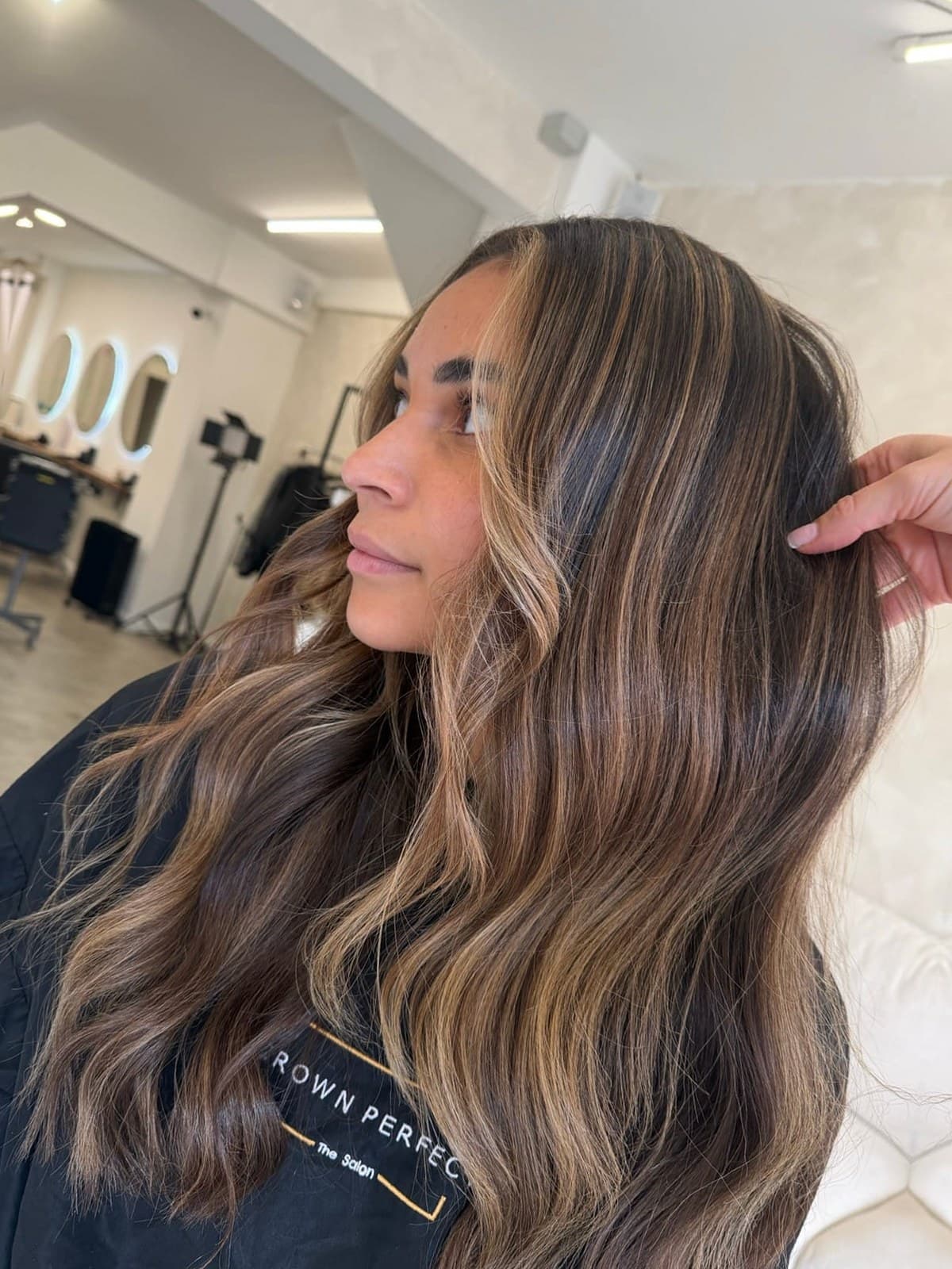 Long brunette with bright, caramel balayage worked through the lengths and soft waves.