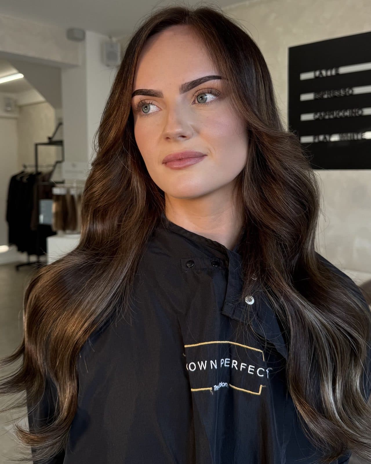 Long, rich brunette with soft caramel lights, blow-dried into loose, glossy waves.