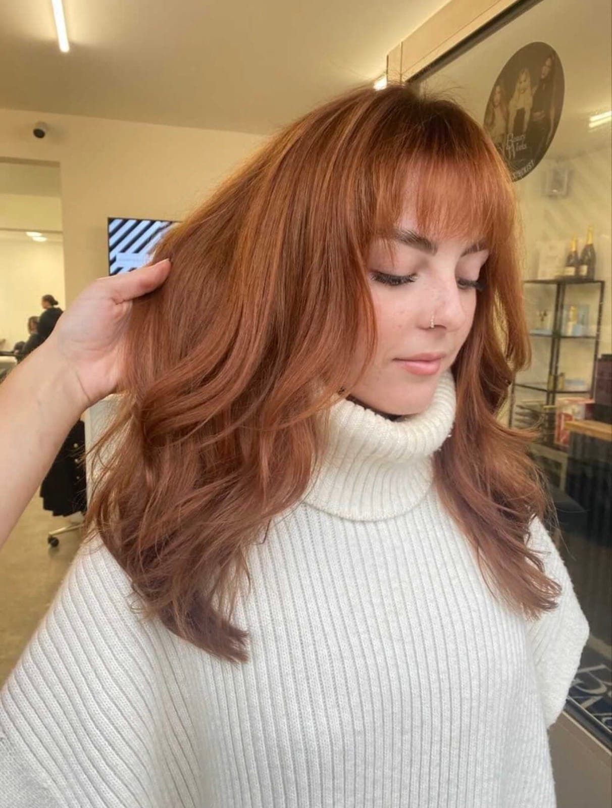 Copper hair with a soft fringe, styled in loose waves.