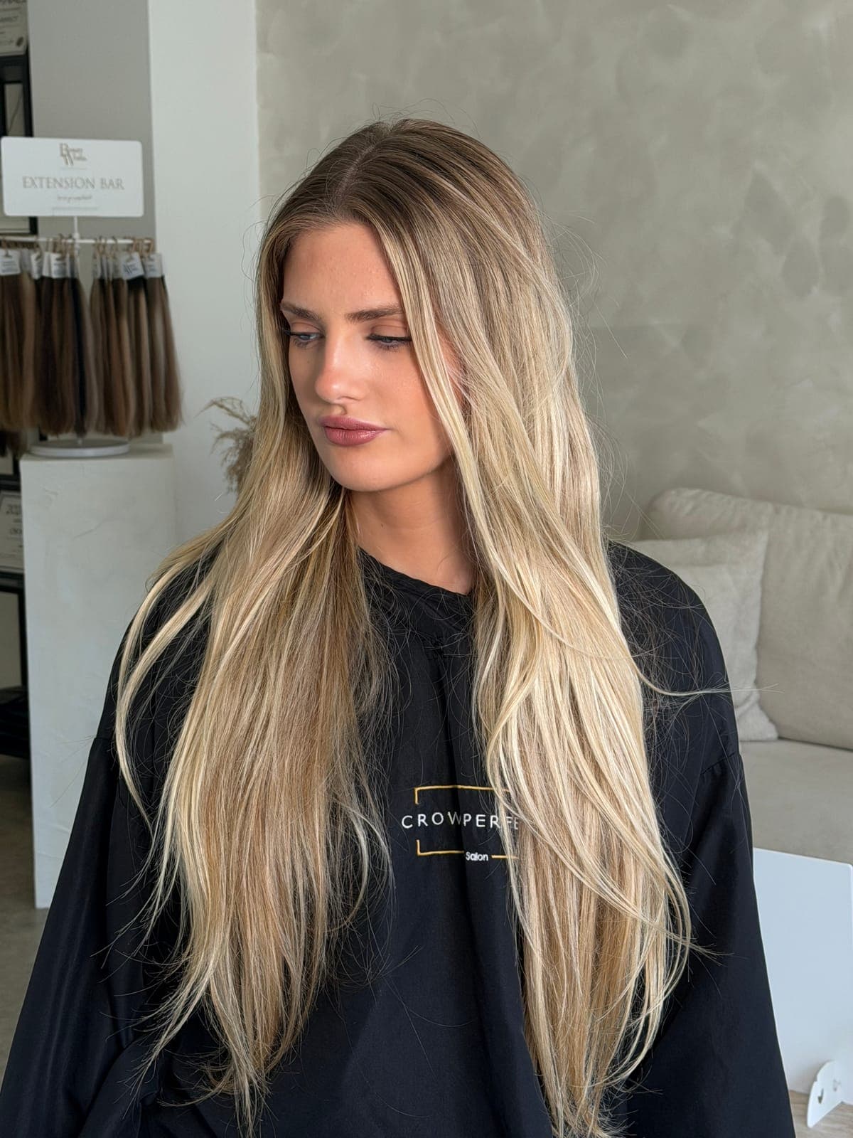 A long, flat blonde with darker roots refreshed into a brighter, dimensional blonde with face-framing pieces and soft waves, before